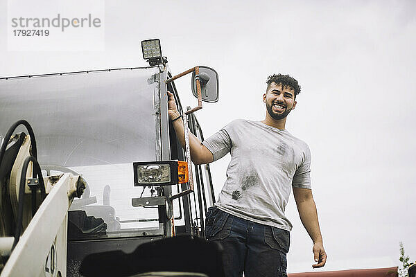 Porträt eines glücklichen Bauarbeiters  der an der Tür eines Fahrzeugs steht