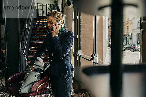Weibliche Fachkraft  die in einer Hotelhalle mit einem Mobiltelefon spricht