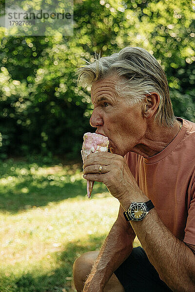 Älterer Mann isst Eis im Park