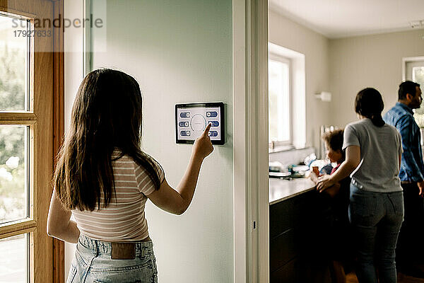 Mädchen  das eine Smart-Home-App auf einem digitalen Tablet benutzt  während es in der Nähe der Tür steht