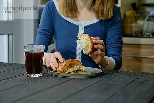 Nahaufnahme von Frauenhänden mit einem Croissant (selektiver Fokus)