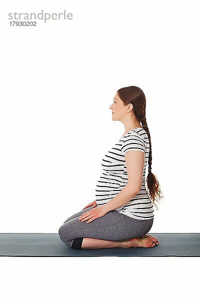 Schwangerschaft Yoga-Übung  schwangere Frau tut Yoga asana Virasana Hero Pose auf Knien vor weißem Hintergrund