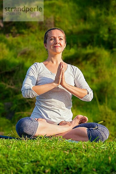 Meditation und Entspannung Yoga im Freien  junge Frau meditiert und entspannt in Padmasana Lotus Pose) mit Kinn Mudra auf grünem Gras im Wald