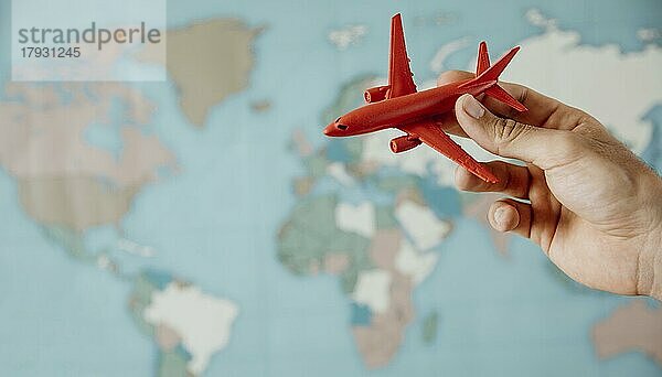 Seitenansicht von Person hält Flugzeug Figur über Karte  Auflösung und hohe Qualität schönes Foto
