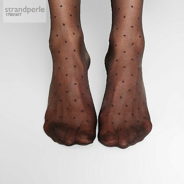 Draufsicht auf weibliche Beine in transparenten Strumpfhosen mit klassischem Tupfenmuster