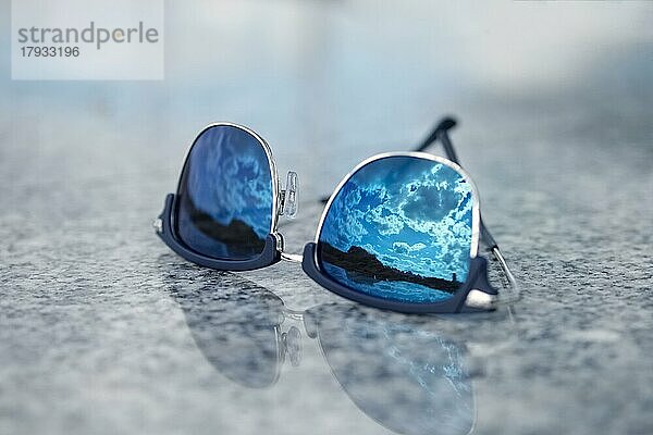 Sonnenbrille mit Reflexion des blauen Himmels im Glas. Selektiver Fokus Foto