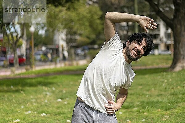 Porträt eines gut aussehenden  attraktiven  reifen  bärtigen  athletischen  lateinamerikanischen Mannes in den 40ern  der Dehnübungen macht und sich auf ein morgendliches Training im Park vorbereitet