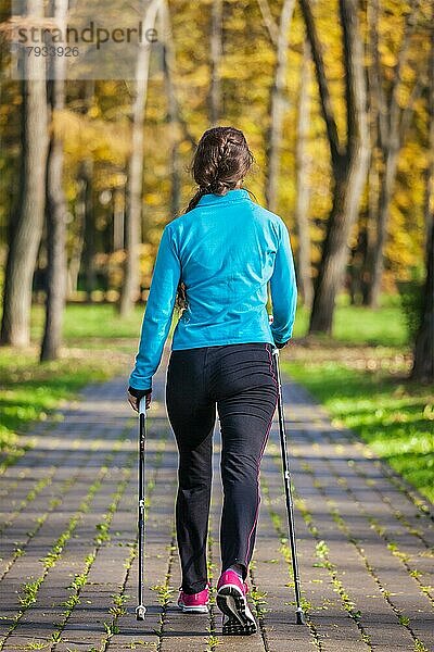 Nordic-Walking-Abenteuer und Trainingskonzept  Frau wandert mit Nordic-Walking-Stöcken im Park
