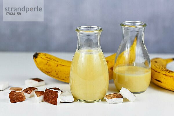 Helathy gelbes Bananen Kokosnuss Smoothie Getränk in Gläsern neben den Zutaten