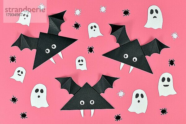 Schwarzes Papier Vampirfledermäuse mit lustigen Kulleraugen und und Geister und Spinne geformt Konfetti auf rosa Halloween Hintergrund