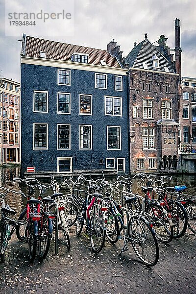 Fahrräder in einer Amsterdamer Straße in der Nähe einer Gracht mit alten Häusern. Amsterdam  Niederlande  Europa