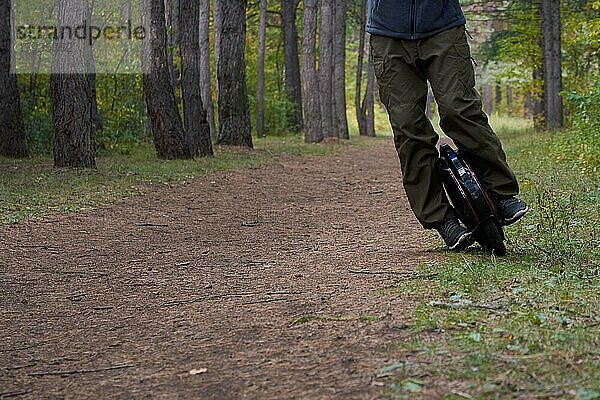 Vorderansicht der männlichen Beine auf einem Einrad im Wald