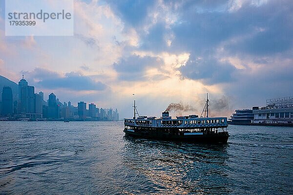 Hong Kong Skyline Stadtbild Downtown Wolkenkratzer über Victoria Harbour auf Sonnenuntergang mit Touristen Fähre Boot Silhouette. Hongkong  China  Asien