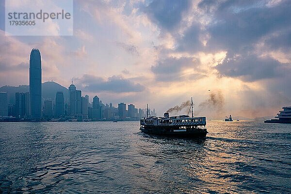 Hong Kong Skyline Stadtbild Downtown Wolkenkratzer über Victoria Harbour auf Sonnenuntergang mit Touristen Fähre Boot Silhouette. Hongkong  China  Asien