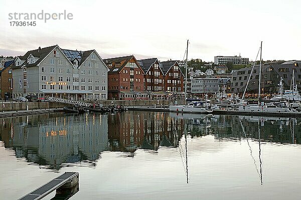 Gebäude und Boote spiegeln sich am Abend im Hafenbecken von Tromsö  Troms og Finnmark  Norwegen  Europa