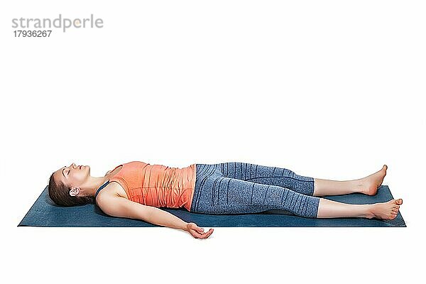 Schöne sportliche fit Frau entspannt in Yoga Asana Savasana  Körperhaltung im Studio vor weißem Hintergrund