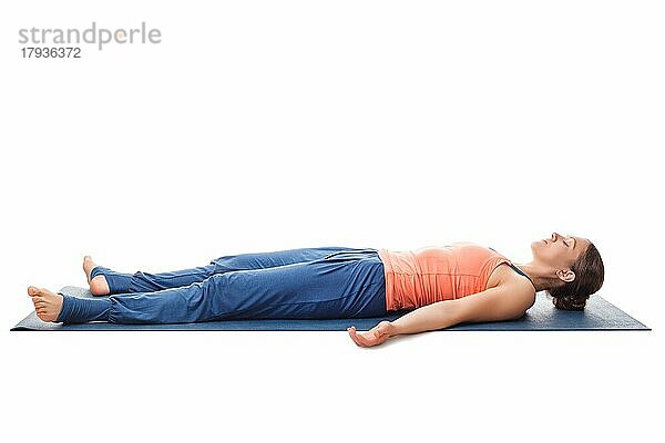Schöne sportliche fit Yogini Frau entspannt sich in Yoga Asana Savasana  Körperhaltung vor weißem Hintergrund