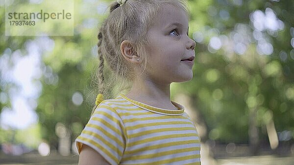 Süßes kleines Mädchen hört Musik und singt mit. Close-up-Porträt von Kind Mädchen steht in einem Stadtpark und hört zu Musik. Odessa  Ukraine  Europa