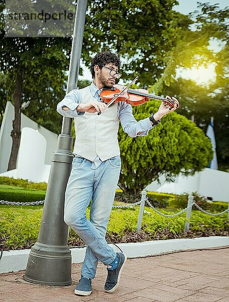 Mann spielt Geige auf der Straße. Porträt eines Geige spielenden Mannes auf der Straße. Jacke Künstler spielt Geige im Freien  Bild einer Person spielt Geige im Freien