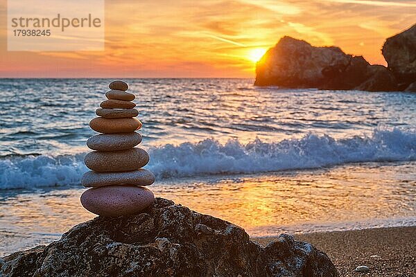 Konzept des Gleichgewichts und der Harmonie. Cairn Stapel von Steinen Kieselsteine Steinhaufen am Strand Küste des Meeres in der Natur auf Sonnenuntergang. Meditative Kunst des Steinstapelns
