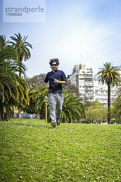 Porträt von gut aussehend attraktiv reifen bärtigen sportlichen lateinischen Mann Kerl 40s in lässigen blauen T-Shirt läuft in einem Park