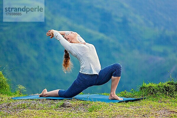 Yoga im Freien  sportlich fitte Frau übt Hatha-Yoga-Asana Anjaneyasana  niedrige halbmondförmige Ausfallschritt-Haltung im Freien im Himalaya-Gebirge