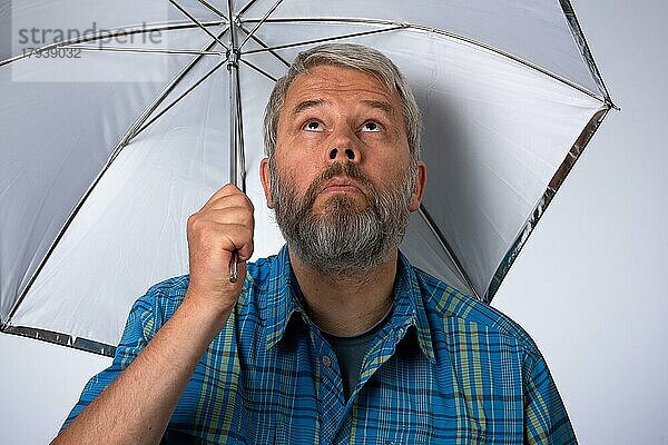 Mann  55 Jahre im Studio hält Regenschirm (eigentlich Reflexschirm)