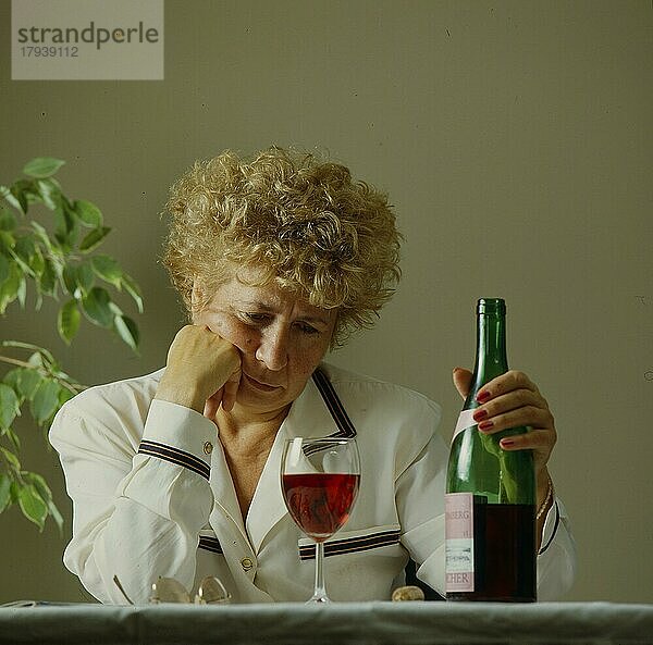 Ältere Frau mit Weinglas und Flasche