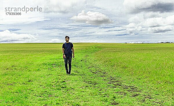 Reisende Mann zu Fuß in der schönen Landschaft. Backpacker Mann zu Fuß in einer Landschaft. Landschaft der Reisende Mann zu Fuß in der grünen Feld. Lifestyle von abenteuerlichen Mann auf dem Feld