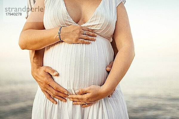 Schwangere Frau mit ihrem Partner  der ihren Bauch in der Natur hält