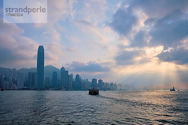 Hong Kong Skyline Stadtbild Downtown Wolkenkratzer über Victoria Harbour auf Sonnenuntergang mit Touristen Fähre Boot Silhouette. Hongkong  China  Asien