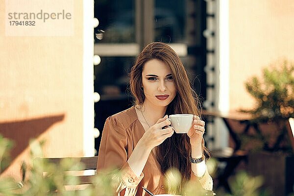 Schöne junge Frau macht Kaffeepause in der Mitte des sonnigen Tages
