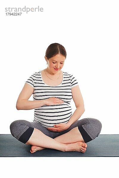 Schwangerschaft Yoga-Übung  schwangere Frau tut asana Sukhasana einfache Yoga-Pose umarmt ihren Bauch vor weißem Hintergrund