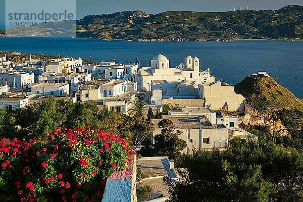 Malerischer Blick auf die griechische Stadt Plaka auf der Insel Milos über rote Geranienblüten und die orthodoxe griechische Kirche. Dorf Plaka  Insel Milos  Griechenland. Fokus auf Gebäude