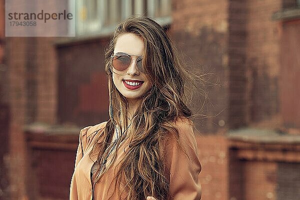 Schöne glückliche junge Frau mit langen lockigen Haaren im Freien
