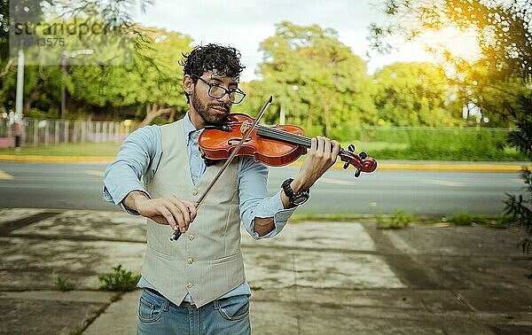 Violinist Künstler spielt eine Melodie im Freien  Porträt von Mann spielt Geige im Freien. Nahaufnahme von Geiger Mann spielt auf der Straße. Bild einer Person spielt die Geige im Freien