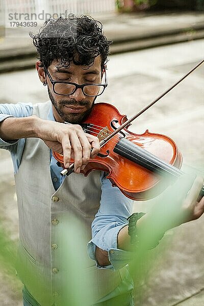 Hübscher Mann in Weste spielt Geige im Freien. Nahaufnahme von Geiger Mann spielt eine Melodie im Freien. Violinist Künstler spielt eine Melodie im Freien
