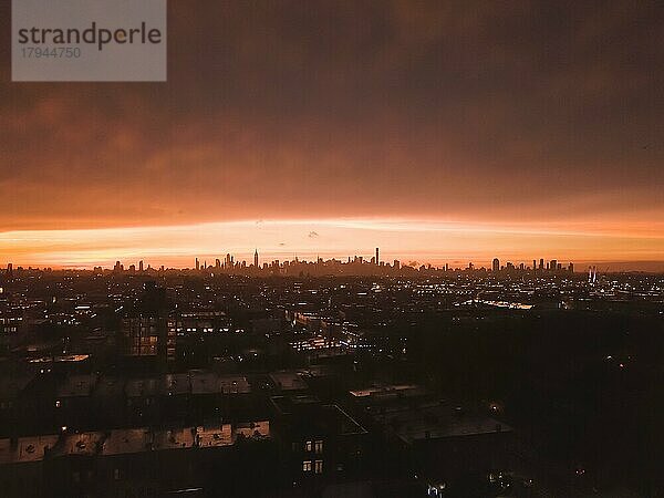 Luftaufnahme von Brooklyn über weit weg Manhattan Skyline in der Ferne nach Sonnenuntergang mit feuerrotem Licht und Wolkenkratzer Silhouette HQ