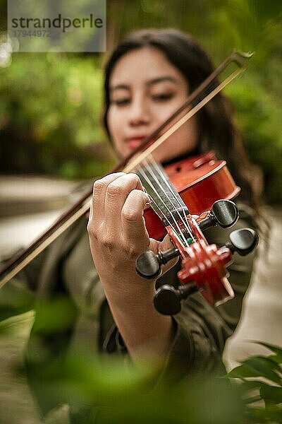 Lifestyle von Mädchen mit ihrer Geige spielen eine Melodie im Freien  Konzept der lächelnden weiblichen Violinist. Lateinisches Mädchen spielt Geige im Freien. Porträt eines lateinischen Mädchens  das im Freien Geige spielt