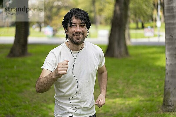 Porträt von gut aussehend attraktiv reifen bärtigen sportlichen lateinischen Mann Mann 40s in lässig weißes T-Shirt läuft in einem Park