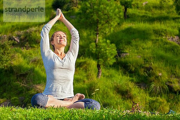 Meditation und Entspannung Yoga im Freien  junge Frau meditiert und entspannt in Padmasana Lotus Pose) auf grünem Gras im Wald