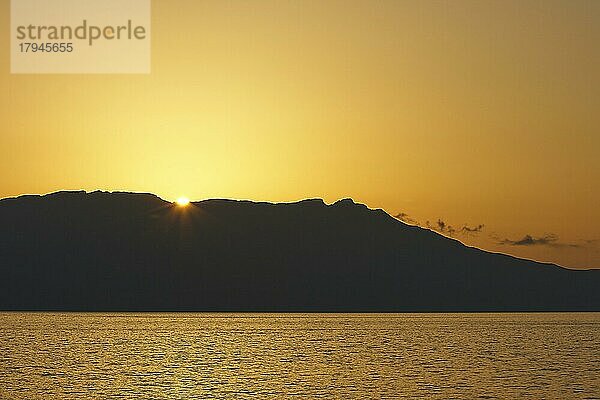 Sonnenuntergang  Abendlicht  Halbinsel Rodopou  Halbinsel Gramvoussa  Gramvoussa als Silhouette  Sonne knapp über Berggrat  bronzefarbener Himmel  Westkreta  Insel Kreta  Griechenland  Europa