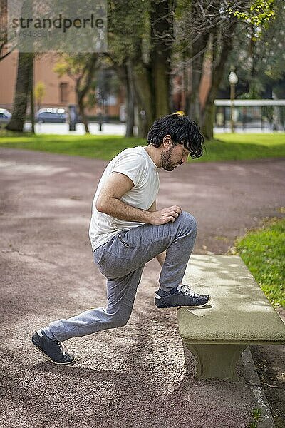 Porträt eines gut aussehenden  attraktiven  reifen  bärtigen  athletischen  lateinamerikanischen Mannes in den 40ern  der Dehnübungen macht und sich auf ein morgendliches Training im Park vorbereitet