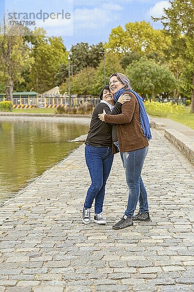 Lesbisches Paar umarmt sich lachend in einem Park