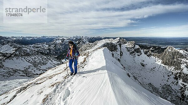 Bergsteigerin an einem felsigen verschneiten Grat  Wanderweg zur Ammergauer Hochplatte  Ausblick auf Bergpanorama  Hinten Gipfel Krähe  im Herbst  Ammergauer Alpen  Bayern  Deutschland  Europa