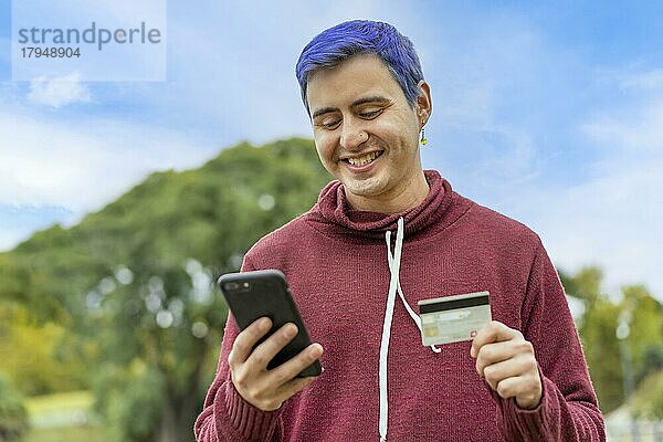 Latin Gay Mann verwendet Kreditkarte  um Online-Zahlung auf Smartphone zu machen. gemischtrassiger Mann verwendet Mobiltelefon für Online-Shopping. Ein Mann benutzt sein Smartphone  um Kreditkartentransaktionen über eine App zu überprüfen. Textfreiraum