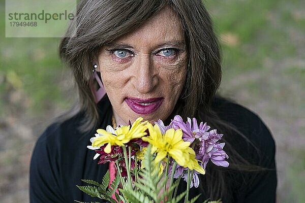 Porträt einer reifen Transgender-Frau mit einem Blumenstrauß von oben gesehen