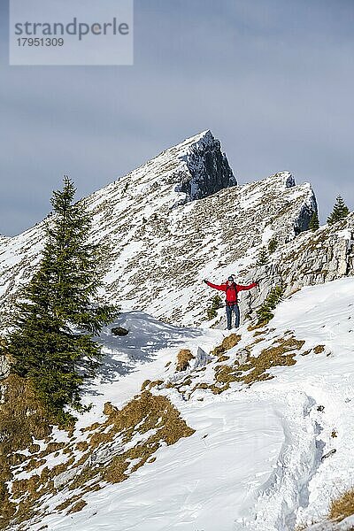 Fröhlicher Wanderer streckt Arme in die Luft  Wanderweg im Winter  Weg zur Ammergauer Hochplatte  Ammergauer Alpen  Bayern  Deutschland  Europa