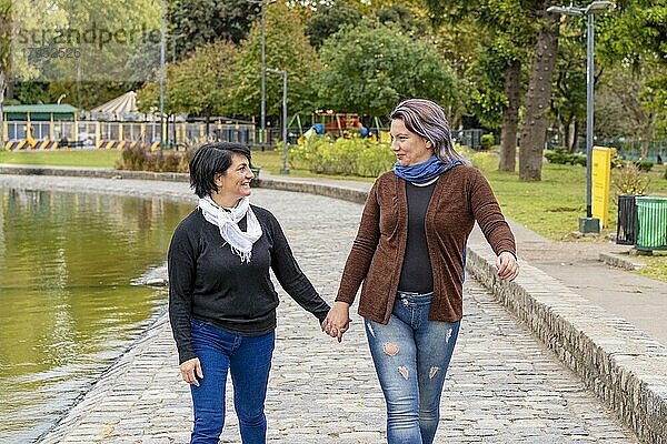 Lesbisches Paar in einem Park  das sich an den Händen hält und sich gegenseitig anschaut