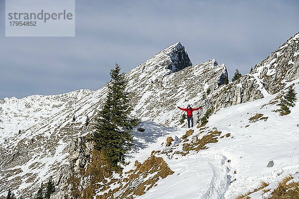 Fröhlicher Wanderer streckt Arme in die Luft  Wanderweg im Winter  Weg zur Ammergauer Hochplatte  Ammergauer Alpen  Bayern  Deutschland  Europa